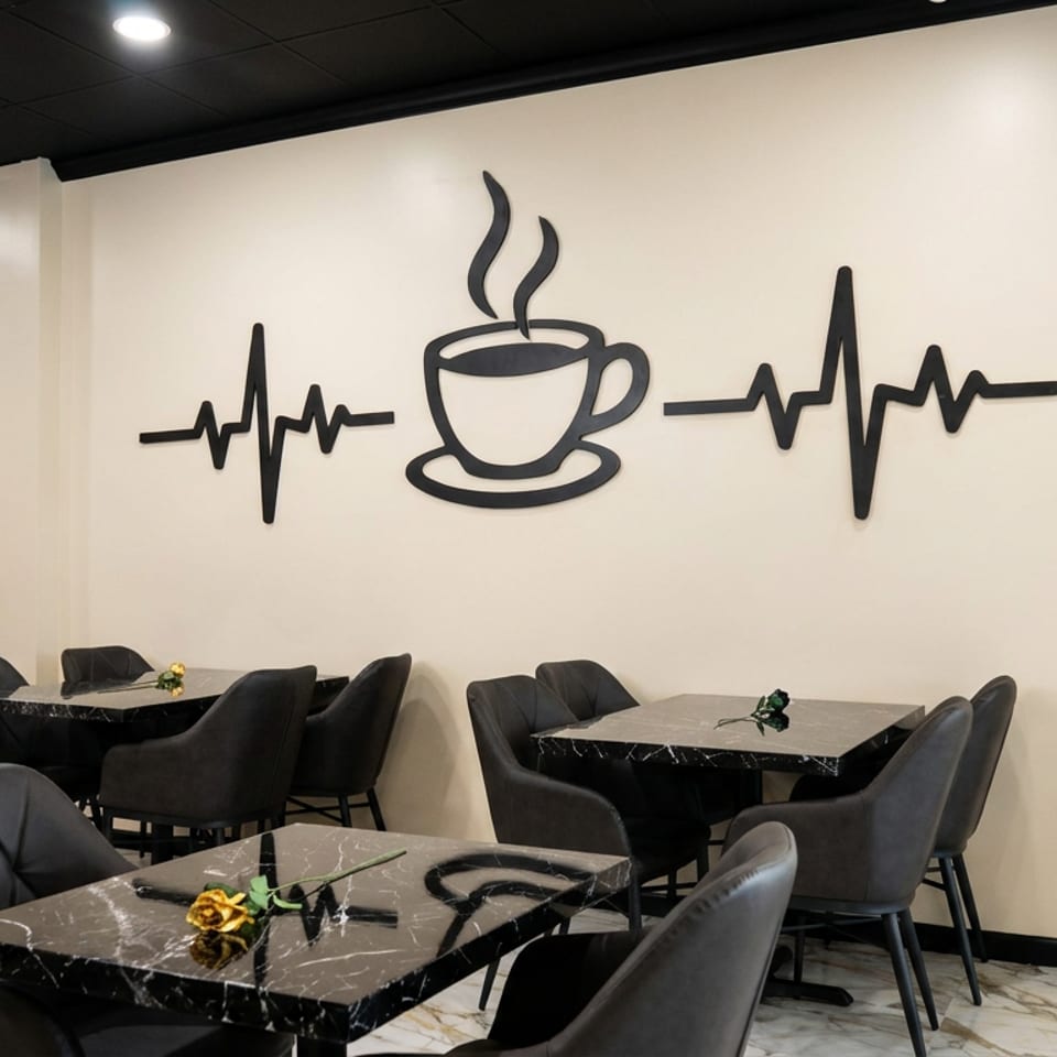 Modern café dining area with black marble tables, upholstered chairs, and a steaming coffee cup with heartbeat wall decor.